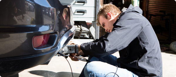 A student works on repairing a car.